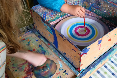 Kinder bedienen hier die Farbdrehscheibe, mit der bunte Bilder mit Kreisen entstehen.