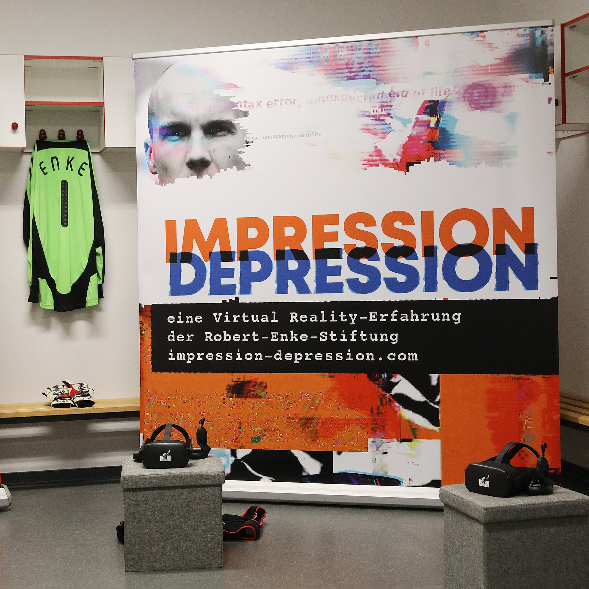 Auf dem Foto ist ein Umkleideraum zu sehen. An einem Kleiderhaken hängt ein Torwarttrikot mit dem Namen Enke darauf. Daneben befindet sich ein Roll Up mit dem Titel der Ausstellung "Impression Depression". Auf kleinen Podesten liegen zwei VR-Brillen.