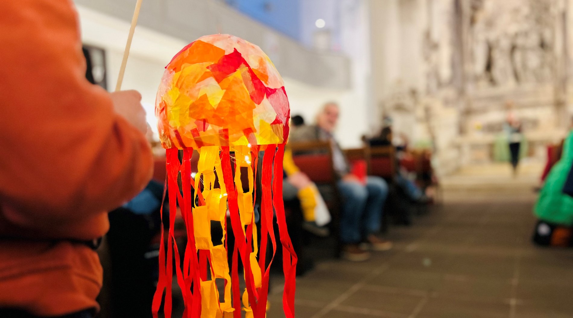 Ein Kind hält einen selbstgebastelten Lampion in der Hand. 