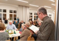 Hier sind verschiedene Personen in Aktion zu sehen, wie sie im voll besetzten Saal während des Empfangs einen kleinen Sketch vortragen, bei dem aus Gesprächen am Seelsorgetelefon zitiert wurde.