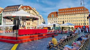 Dieses Bild zeigt das Publikum des Palais Sommers von hinten mit Blick zur Bühne von einem anderen Winkel aus. Auf der Bühne istr das Ensemble zu sehen.