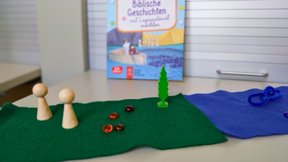 Dieses Bild zeigt ein Montessori-Spieltablett mit verschiedenen Stoffen und Figuren.