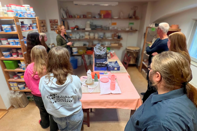 Mitarbeitende der Psychosozialen Kontakt- und Beratungsstelle Dresden erklären Schülerinnen und Schülern ihre Arbeit. Dabei befinden sie sich in der Töpferwerkstatt der Einrichtung.