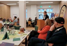 Auf diesem Foto ist Katharina Pruggmayer-Gruhn, Koordinatorin der Telefonseelsorge Dresden, bei Ihrer Rede zu sehen. An den Tischen rund um das Rednerpult sitzen verschiedene Gäste.