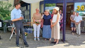 Auf diesem Bild zu sehen sind Geschäftsführer Sven Marschel am Mikrofon, die interimsmäßige Heimleiterin Romy Meißner sowie die Leiterinnen der Abteilung Altenhilfe Prof. Dr. Kathrin Engel und Christin Großmann (von links nach rechts). Sie stehen vor dem Eingang der "Friedenshöhe", weiter im Hintergrund sind weitere Mitarbeitende zu sehen sowie ein Luftballon mit großer "30".