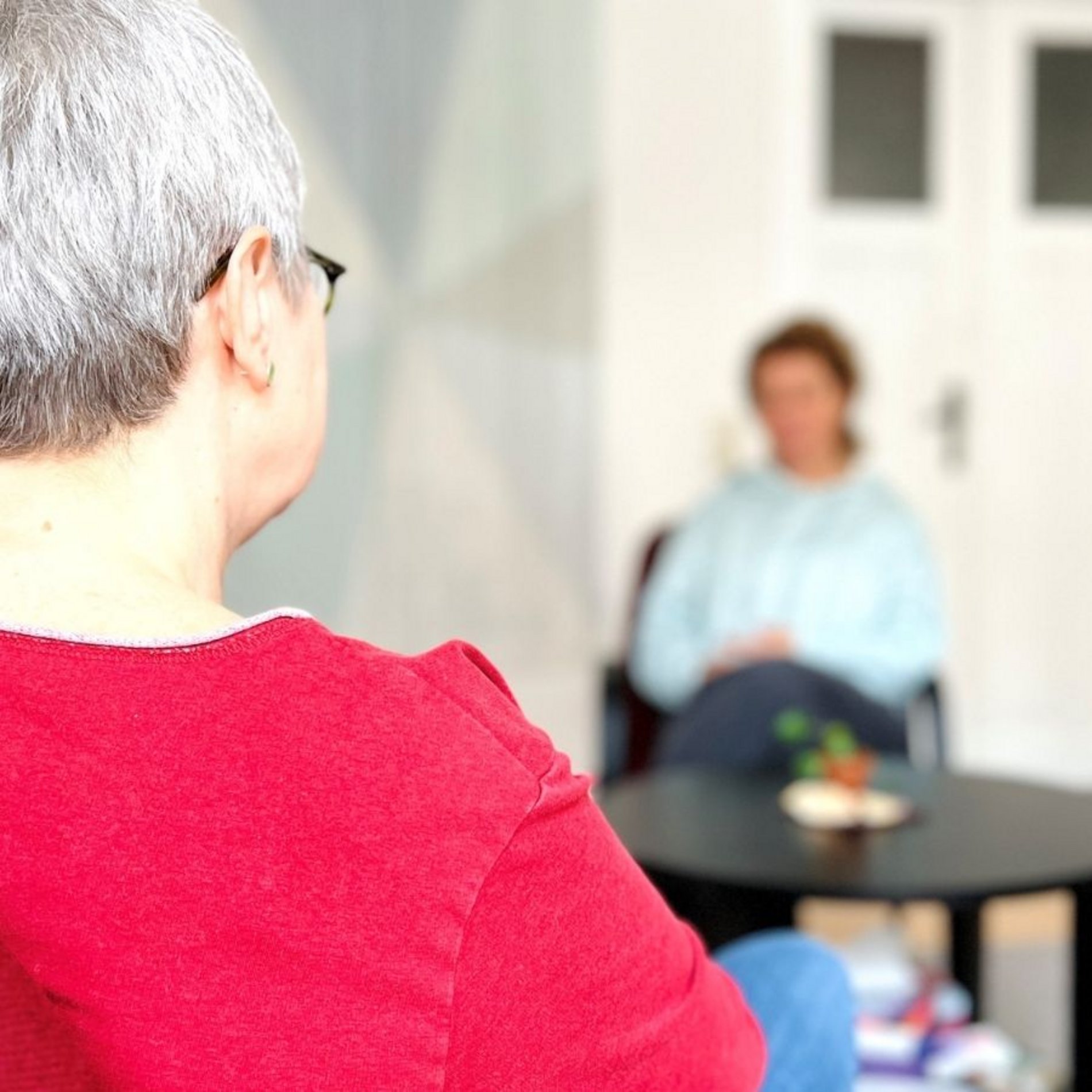 Dieses Bild zeigt eine Beratungssituation. Zwei Frauen sitzen sich gegenüber an einem Tisch in der Evangelischen Beratungsstelle Dresden.
