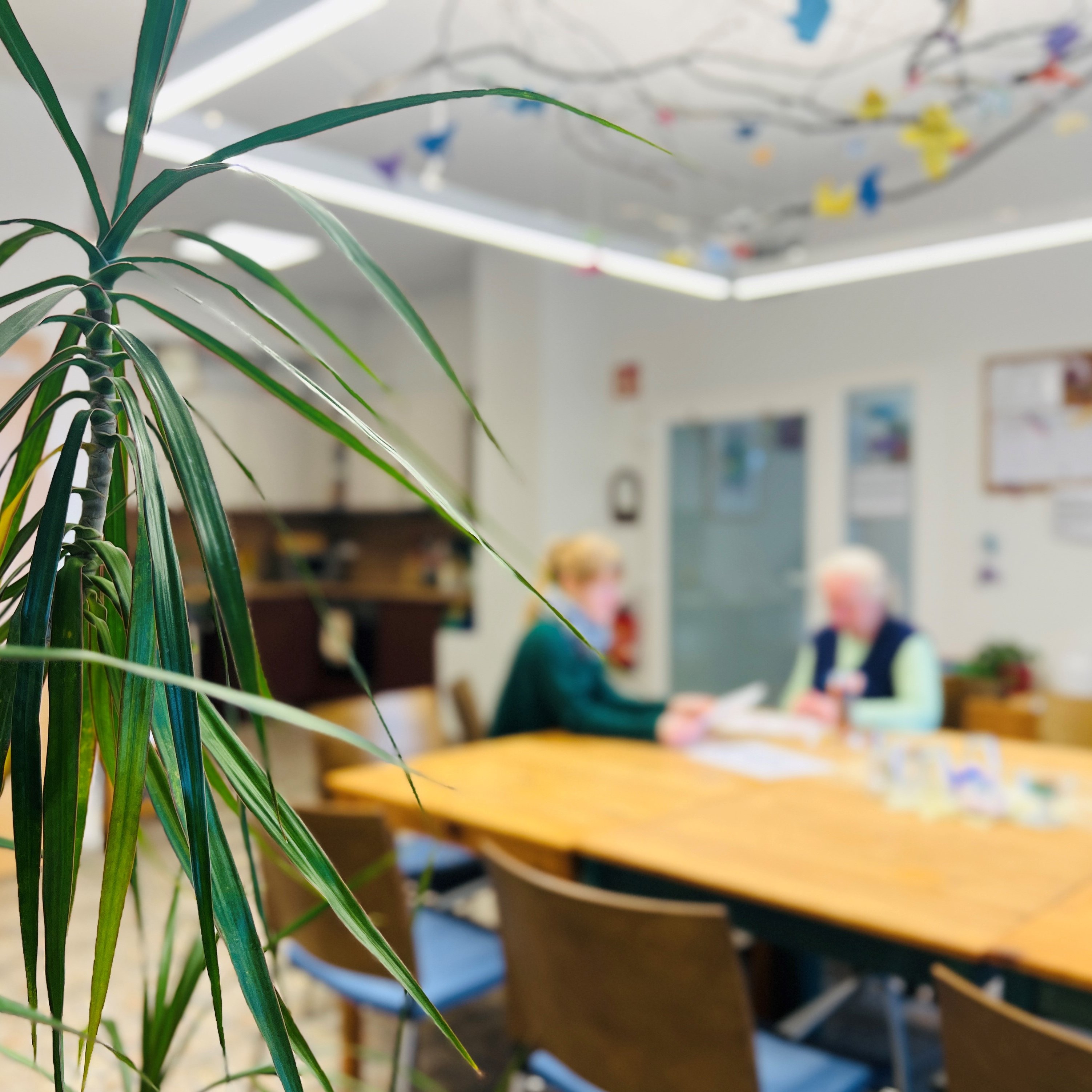 Das Bild zeigt zwei Personen, die an einem Tisch sitzen und sich unterhalten.