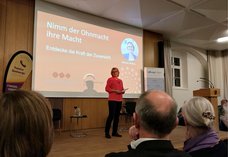 Dieses Foto zeigt die Autorin Melanie Wolfers auf der Bühne zu Beginn ihres Vortrags.