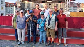 Dieses Foto ist ein Gruppen Bild der "Königskinder" am Ende der Aufführung auf der Bühne zusammen mit Thomas Slesazeck. Alle freuen sich über den gelungenen Auftritt.