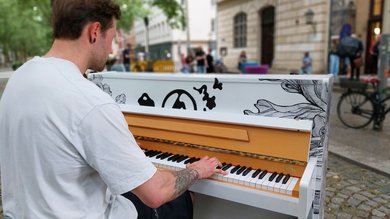 Das Bild zeigt einen Mann, der am Klavier sitzt. 