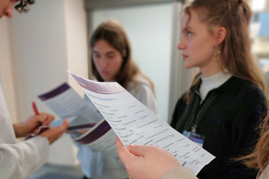 Drei Jugendliche befinden sich im Gespräch während sie einen Fragebogen in ihren Händen halten. 