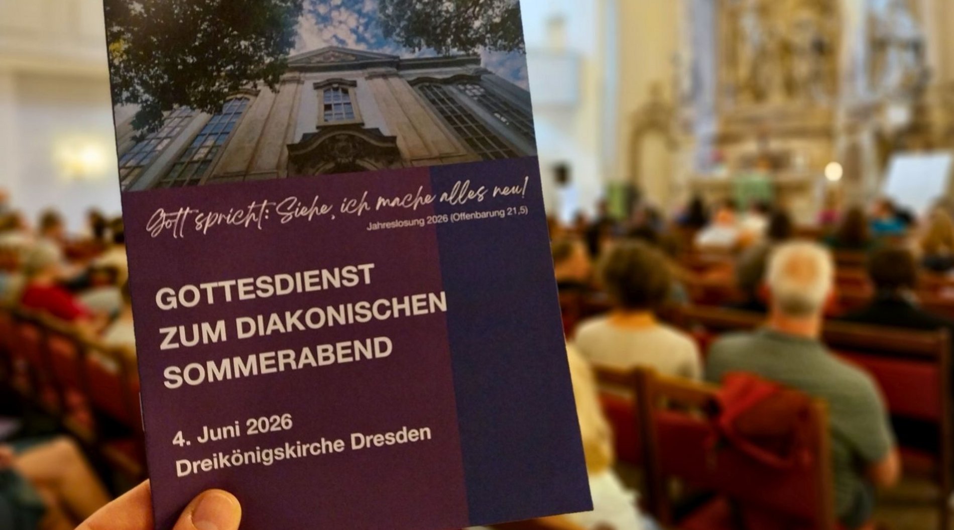 Das Bild zeigt das Liedblatt zum Gottesdienst. Im Hintergrund ist der Kirchraum mit Menschen zu erkennen. 