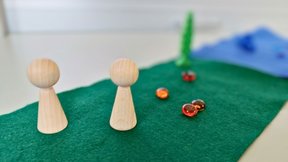 Dieses Bild zeigt ein Montessori-Spieltablett mit verschiedenen Stoffen und Figuren.