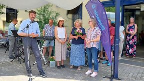 Auf diesem Bild zu sehen sind Geschäftsführer Sven Marschel am Mikrofon, die Leiterinnen der Abteilung Altenhilfe Christin Großmann und Prof. Dr. Kathrin Engel sowie die neue Heimleiterin Linda Pingel (von links nach rechts). Sie stehen vor dem Eingang der "Friedenshöhe", im Hintergrund sind noch andere Personen zu erkennen.