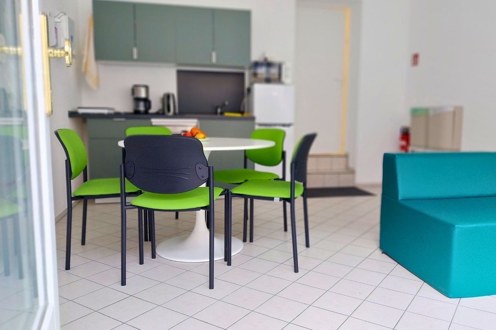 Das Bild zeigt den Gemeinschaftsraum in der "Koje" mit Küchenzeile, Essbereich und Sofaecke.