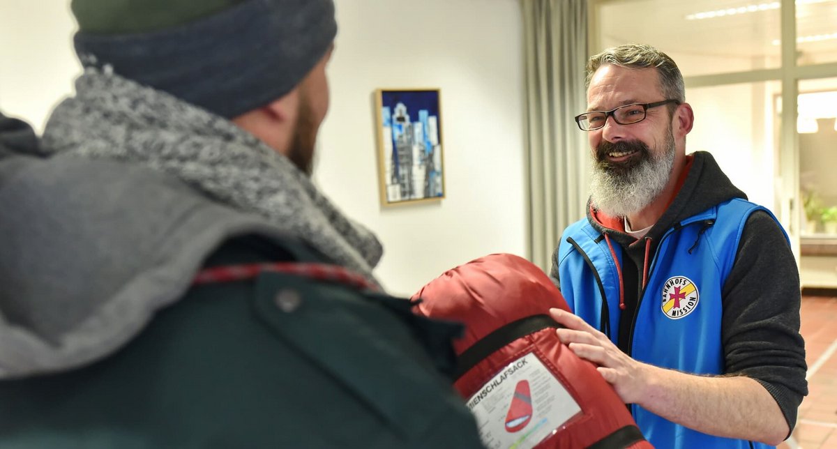 Mitarbeiter Bahnhofsmission gibt Schlafsack