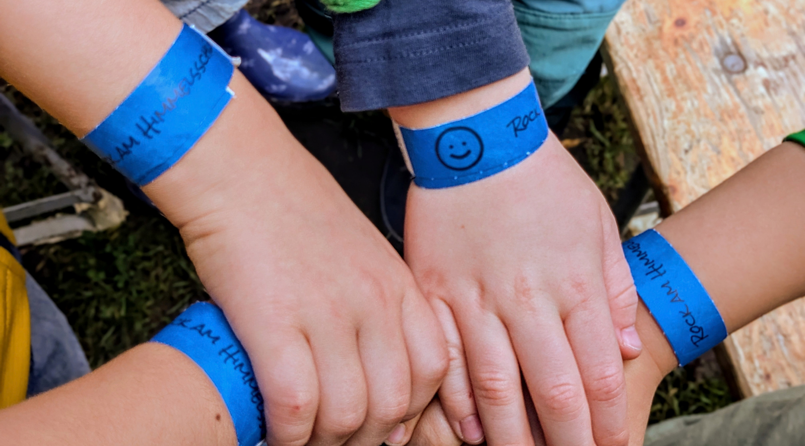 Das Bild zeigt KInderhände, die sich gegenseitig halten. Sie tragen Festivalbänder