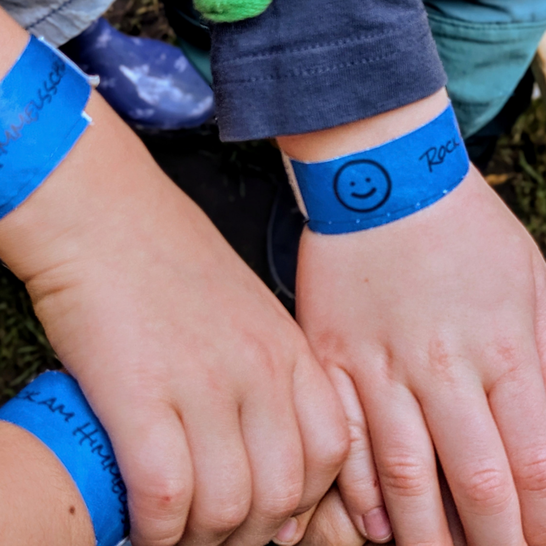 Das Bild zeigt KInderhände, die sich gegenseitig halten. Sie tragen Festivalbänder