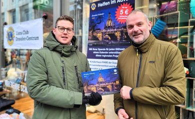Auf dem Bild halten Sandro Junge, Leiter des Kinderhauses Rabe, und Philipp Frenzel vom Lions Club Dresden einen der Dresdner Adventskalender in den Händen.