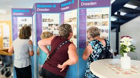 Dieses Bild zeigt Frauen, die sich im Foyer des Altenpflegeheims die Fotoausstellung "30 Jahre Friedenshöhe" anschauen.